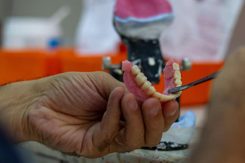 a dental professional making adjustments on a new full arch dental implant.
