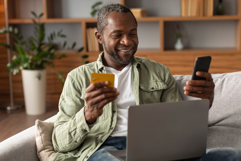 Nice guy with dark hair smiling inputting credit card numbers into laptop for Restore Denture and Implant Center payment