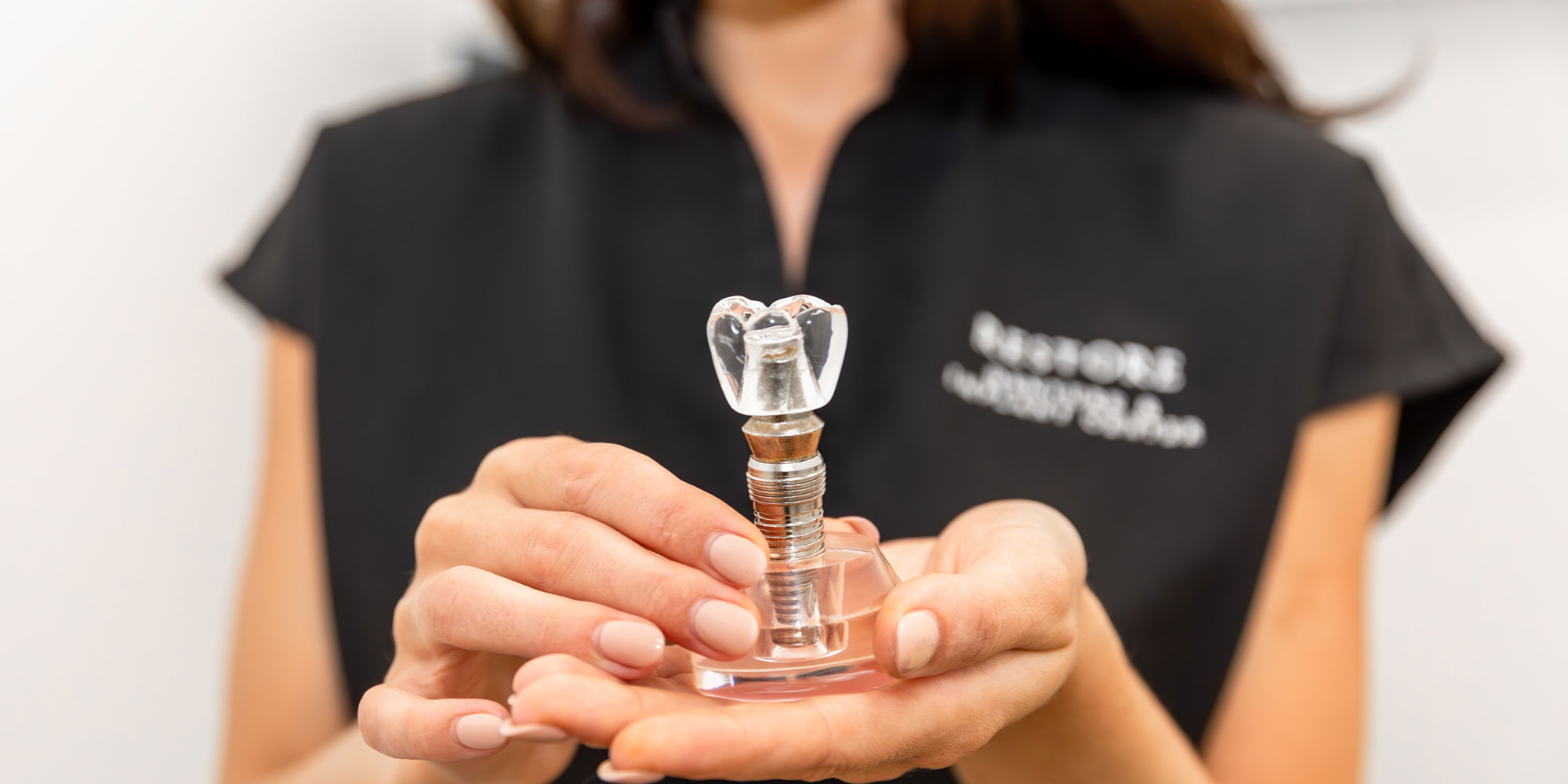 doctor holoding dental implant tooth model within the practice