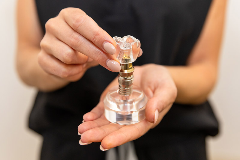 Dr. Alyssa Mencini Holding A Single Dental Implant Model